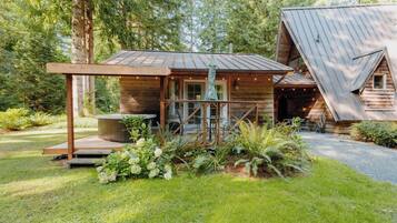 A rustic cabin with a wooden exterior, a covered porch, and a small garden area.