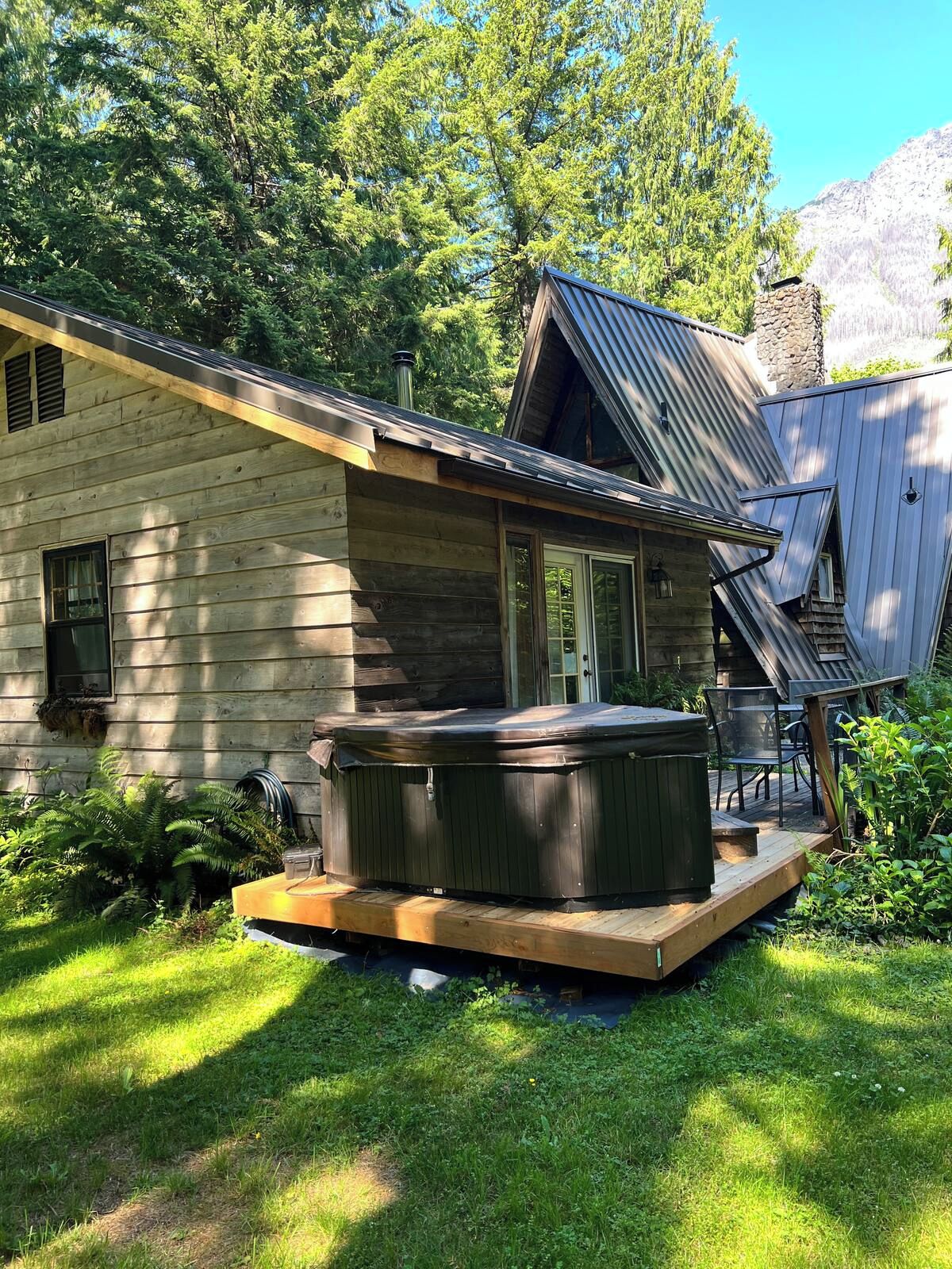 Eine Holzhütte mit Whirlpool und Sitzgelegenheit im Freien.
