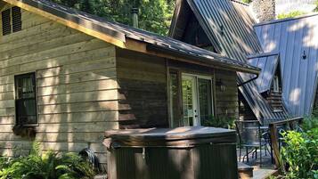 Eine Holzhütte mit Whirlpool und Sitzgelegenheit im Freien.