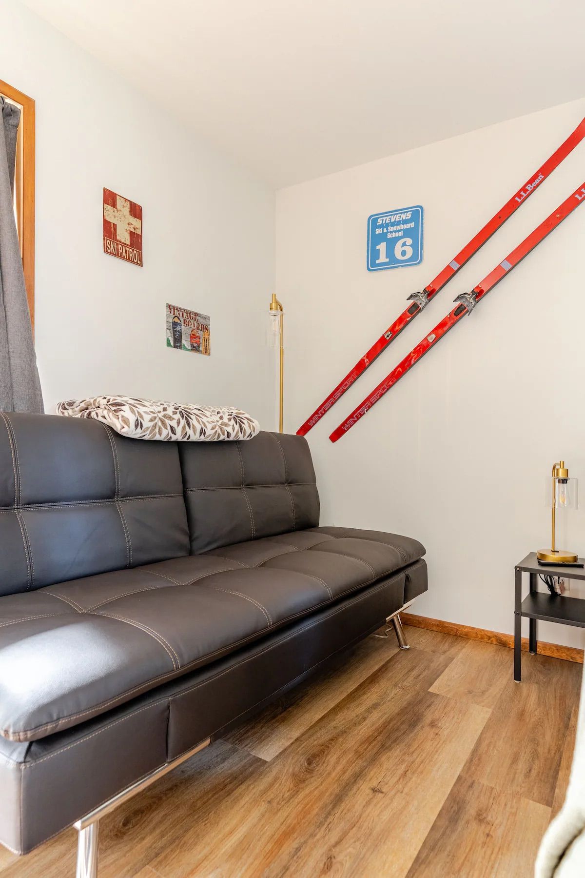 Ein modernes Wohnzimmer mit einer Ledersofa, einem Schild der Skiregierung, einem Schild der Skischule und einem Paar Ski, die an der Wand lehnen.