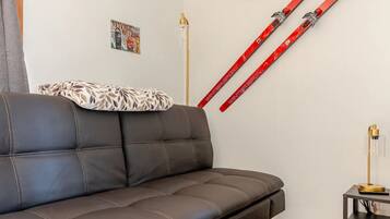 Ein modernes Wohnzimmer mit einer Ledersofa, einem Schild der Skiregierung, einem Schild der Skischule und einem Paar Ski, die an der Wand lehnen.