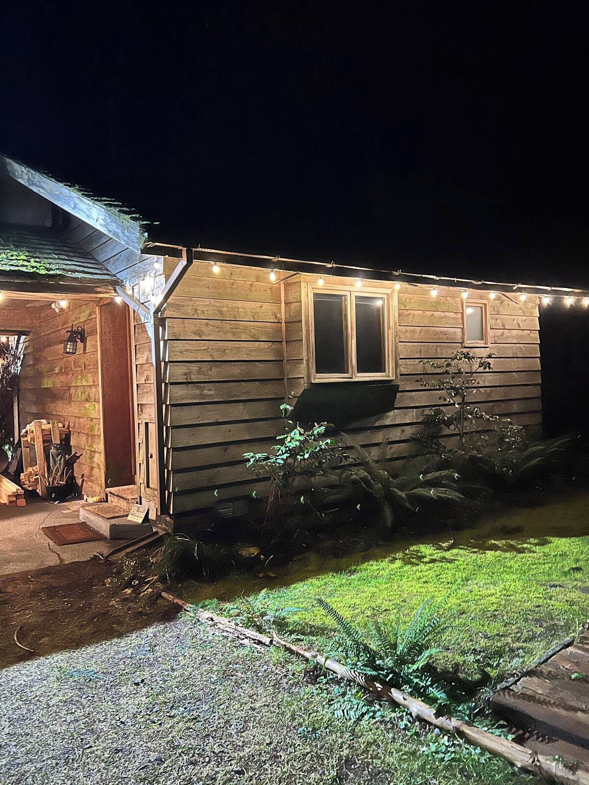 A wooden house with a porch, a window, and string lights.