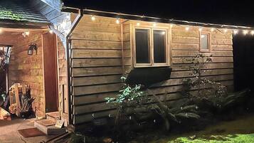 A wooden house with a porch, a window, and string lights.