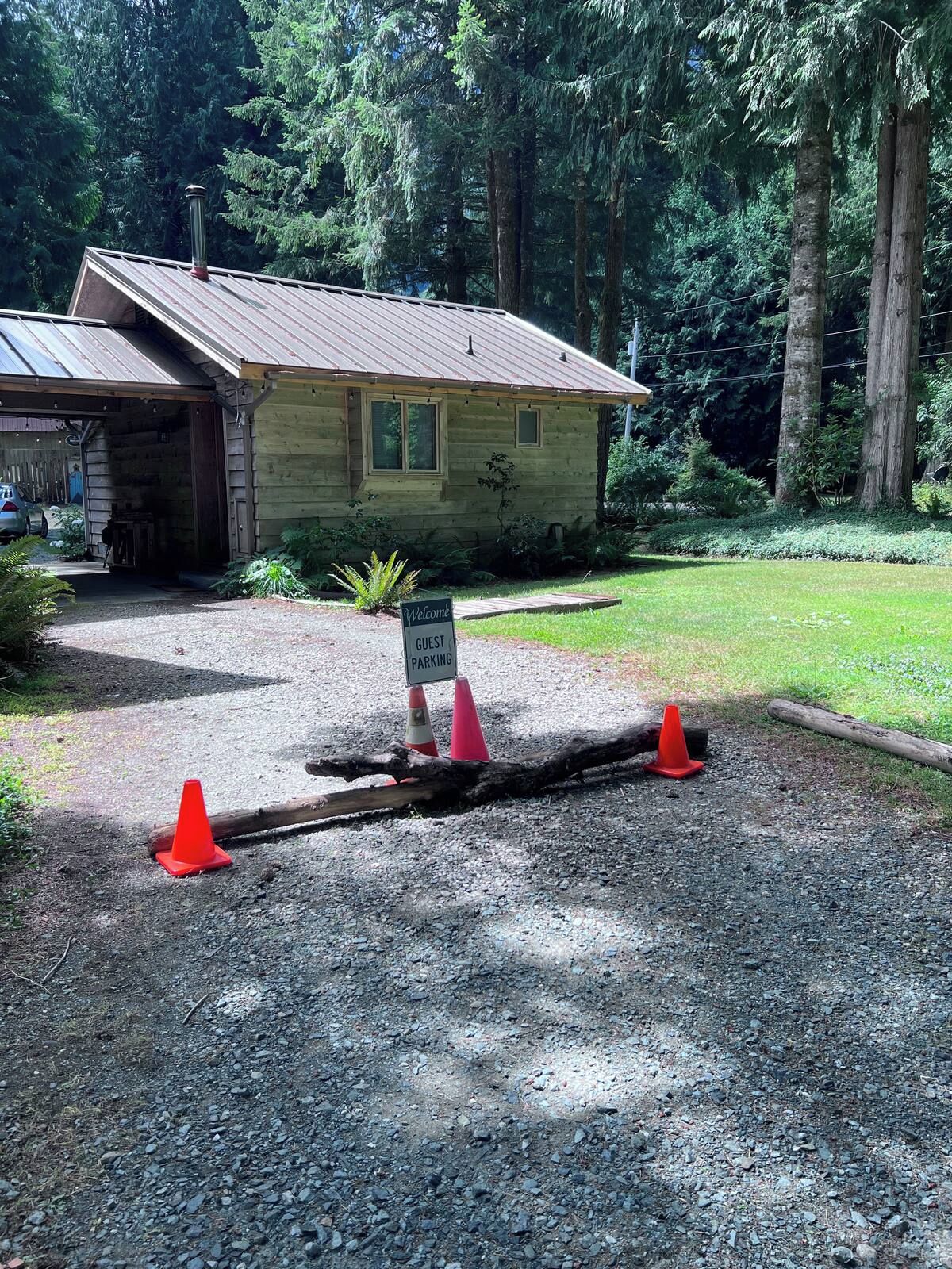 Una cabaña rústica con entrada de grava, rodeada de un bosque denso.