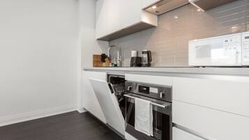 Una cocina moderna con armarios blancos, horno integrado y microondas.