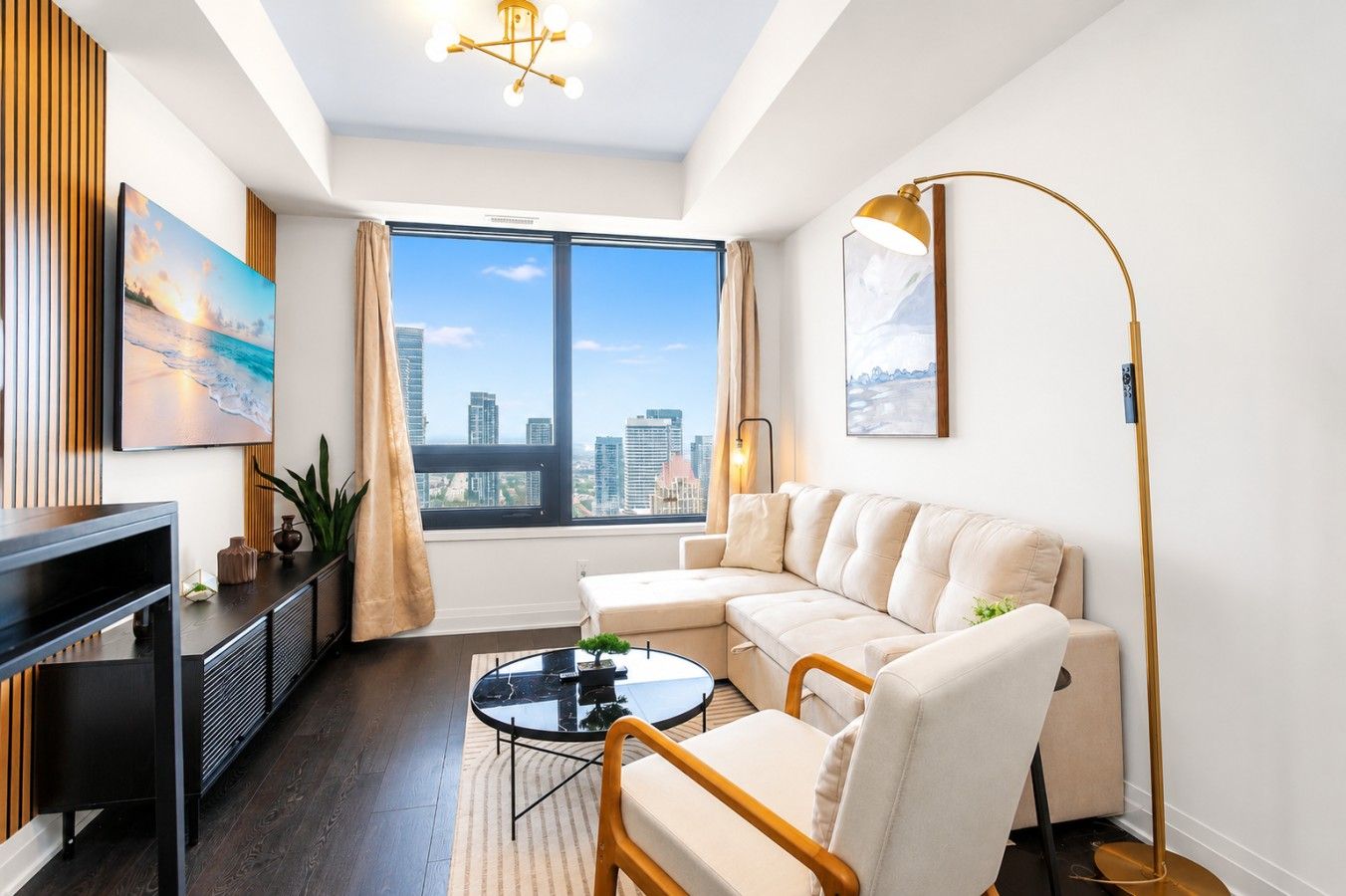 A modern living room with a sectional sofa, a coffee table, a TV, and a large window with a city view.