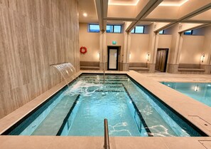 A swimming pool with a lifebuoy, a door, and a bench in a hotel setting. - Luxury Skyline Condo | Pool • Gym • Steps to SQ1 (Mississauga)