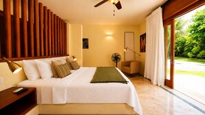 A bedroom with a bed, bedside table, lamp, and a view of greenery outside. - Villa CapCana: 5-Bedroom Villa with Pool, Jacuzzi, Beach, and Golf (Punta Cana)