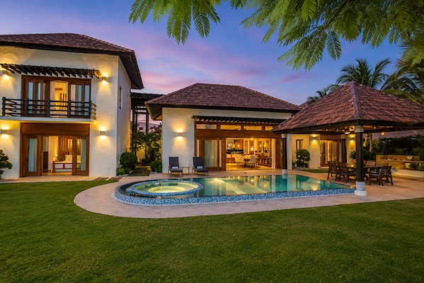 Uma casa de dois andares com piscina, área de estar externa e um pátio bem iluminado.