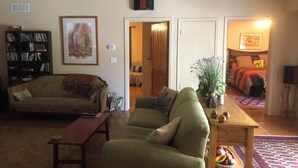 Una sala de estar con un sofá, una mesa de centro, una estantería y una puerta que da a otra habitación.