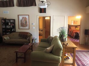 A living room with a sofa, a coffee table, a bookshelf, and a door leading to another room. - Pleasant 2-bedroom Casita in Tucson perfect for a relaxing getaway (Tucson)