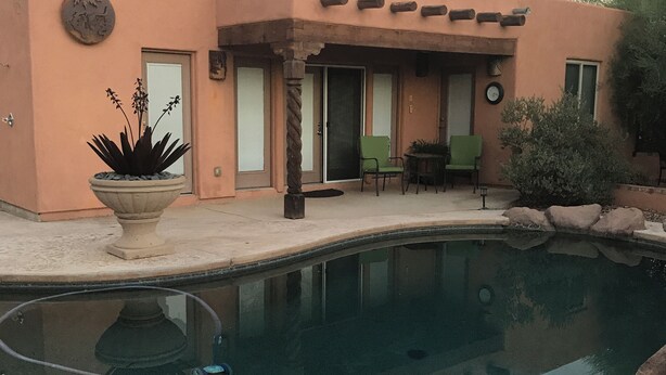 Una casa con piscina, un patio con sillas y una puerta.