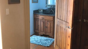 Pasillo que conduce a un baño con puerta de madera, lavamanos y armarios.