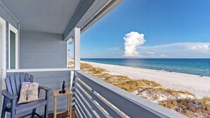 A beach view from a porch with a chair and a small table. - Seawinds 1 by Avantstay Beachfront + Private Beach + Daily Chair Service + 3 Decks (Miramar Beach)