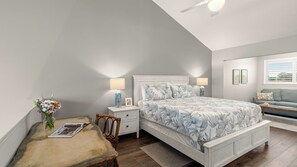 A bedroom with a bed, bedside tables, a chair, a small table with a vase and book, and a window with blinds. - Seawinds 1 by Avantstay Beachfront + Private Beach + Daily Chair Service + 3 Decks (Miramar Beach)