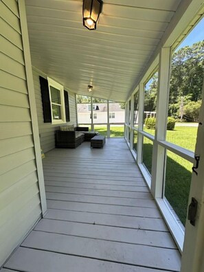 A covered porch with a bench, a lantern, and a view of a lawn and house in the background. - Minutes to Beaches • Self Check-In • Fully Remodeled • Screened Porch • Cozy Fireplace • Washer & Dryer (Wilmington)