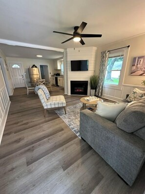 A living room with a fireplace, a sofa, a coffee table, and a ceiling fan. - Minutes to Beaches • Self Check-In • Fully Remodeled • Screened Porch • Cozy Fireplace • Washer & Dryer (Wilmington)