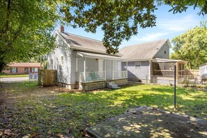 A single-story house with a porch, a fenced yard, and a small detached garage. - Minutes to Downtown • Self Check-In • Fast WiFi • Private Backyard • Free Parking • Sleeps 2 • Linens (Wilmington)