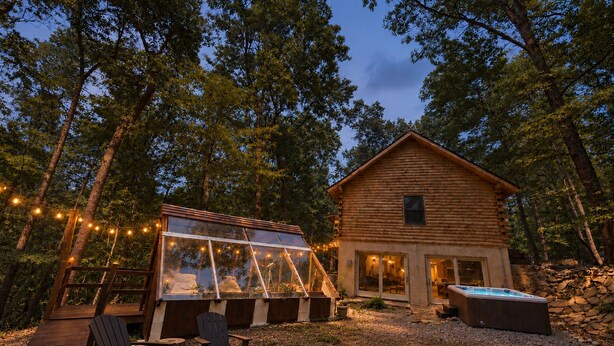 Eine Hütte mit Glasveranda, Sitzgelegenheit im Freien und Whirlpool.