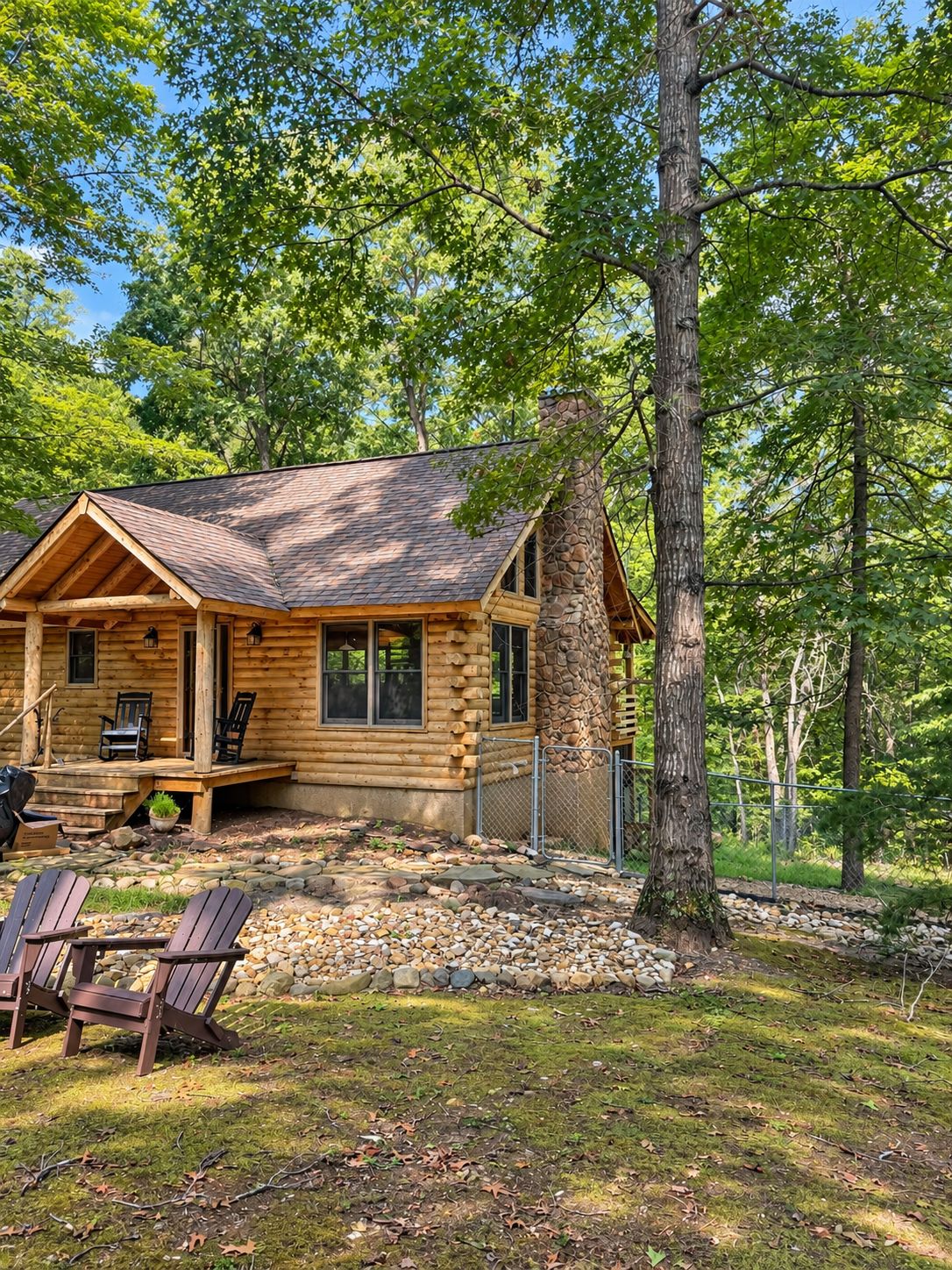 A log cabin with a stone chimney, wooden deck, and outdoor seating.