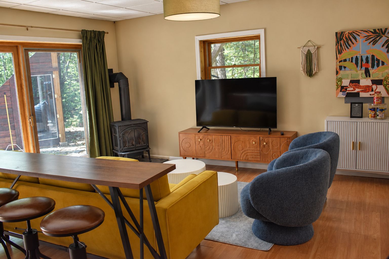 A cozy living room with a television, a wooden cabinet, a blue armchair, and a yellow sofa.