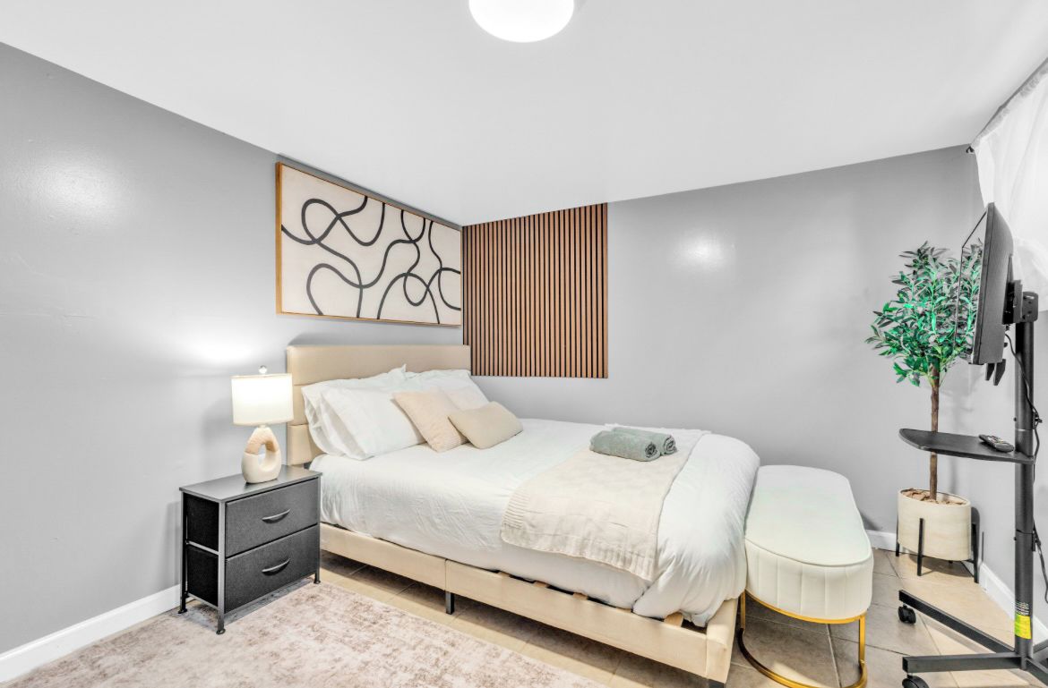 A modern bedroom with a bed, bedside table, lamp, and a television.