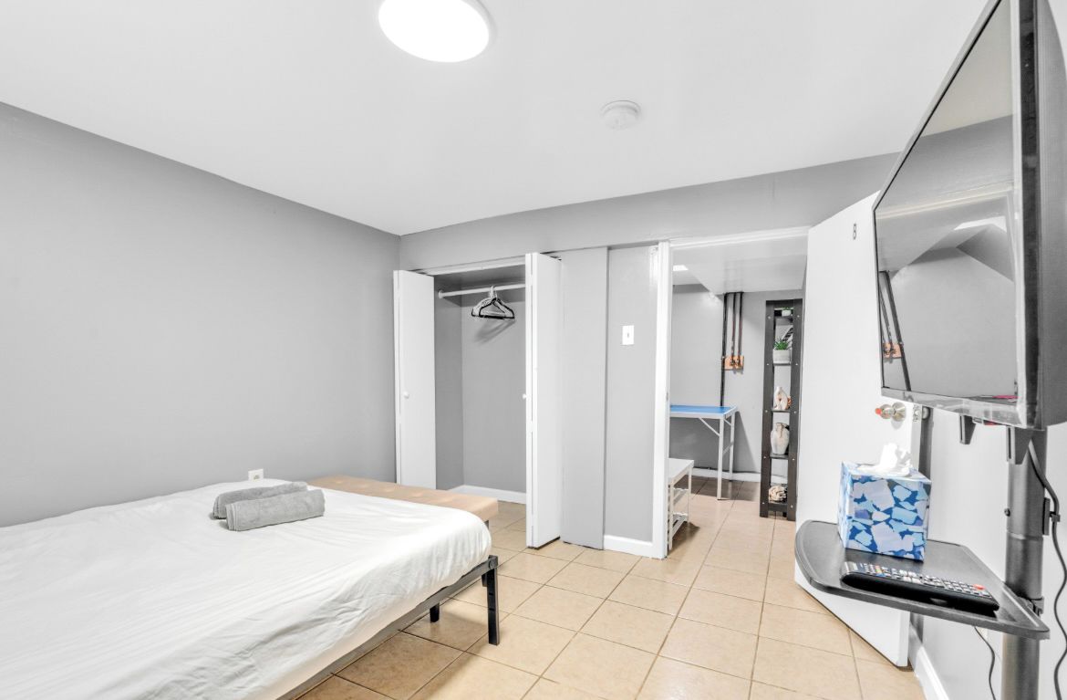 A bedroom with a bed, a TV, a desk, and a bathroom visible through an open door.