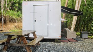 Une remorque mobile équipée d’une porte, d’une table de pique-nique et d’un petit espace de repos abrité.