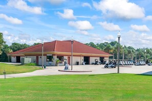 A building with a red roof, a sign for a 'Turn Bar,' and a parking area with golf carts. - Townhome with Shared Pool, Wifi & Full Kitchen (Navarre)