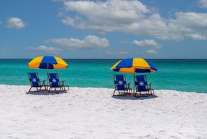 Two beach chairs with matching umbrellas on a sandy beach with a clear view of the ocean. - Townhome with Shared Pool, Wifi & Full Kitchen (Navarre)