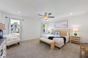 A bedroom with a bed, bedside tables, a bench, a ceiling fan, and a window. - Townhome with Shared Pool, Wifi & Full Kitchen (Navarre)