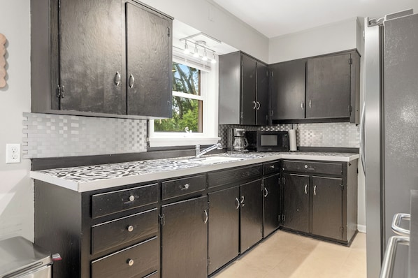 A modern kitchen with dark cabinetry, a tiled backsplash, and a window providing natural light. - Spacious 4-bedroom house in beautiful Hot Springs near Oaklawn (Hot Springs)