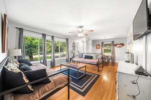 A spacious living area with a sofa, a coffee table, and a dining table. There is a ceiling fan and a window with curtains. - Spacious 4-bedroom house in beautiful Hot Springs near Oaklawn (Hot Springs)
