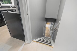 Une cuisine équipée d’une cuisinière intégrée et d’un escalier étroit menant à l’étage supérieur.
