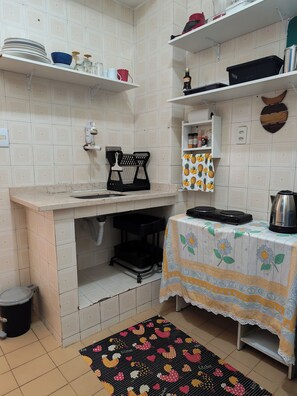 A compact kitchen with a sink, stove, and shelves with kitchenware. - Bright 2BR Apt with Garage Near Ipanema & Copacabana (Rio de Janeiro)