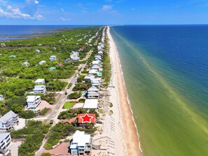 Une zone résidentielle côtière avec des maisons le long de la plage, un ciel dégagé et une mer calme.