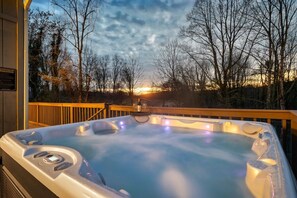 Ein Whirlpool auf einer Holzterrasse mit Sonnenuntergangblick.
