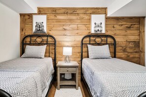 Ein Schlafzimmer mit zwei Betten, einem Holzkopfende, einem Nachttisch mit Lampe und zwei gerahmten Bildern an der Wand.