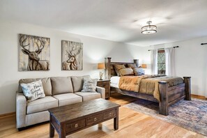 Een slaapkamer met een houten bed, een bank, een nachtkastje en twee wanddecoraties.