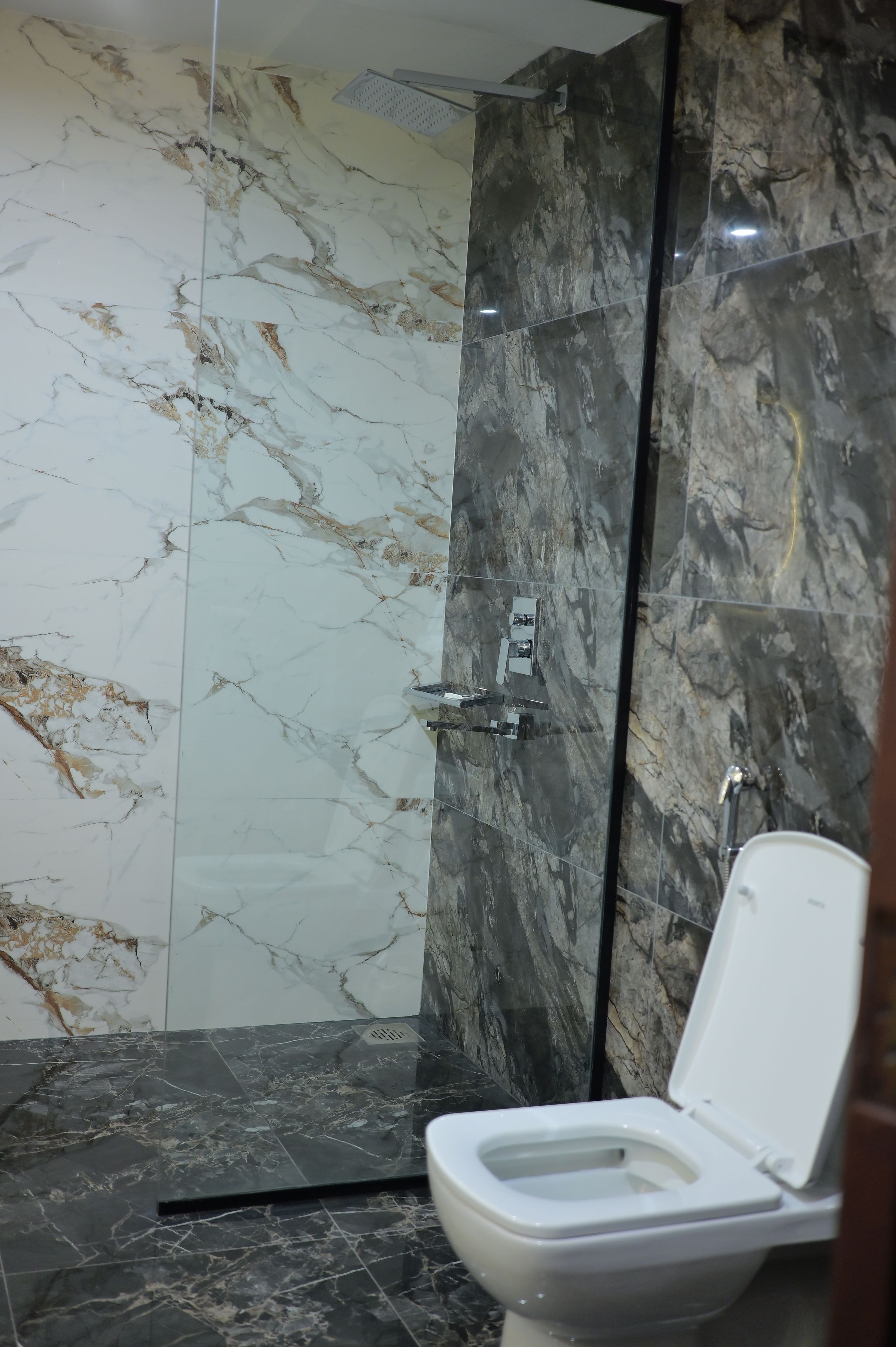 A bathroom with a shower, toilet, and marble walls.
