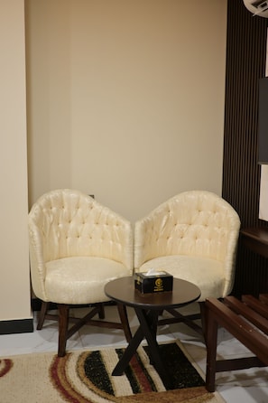 A room with two upholstered chairs facing each other, a small round table, and a patterned rug on the floor.