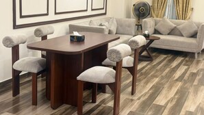 Un área de comedor con una mesa y sillas de madera, un sofá y un ventilador.