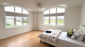 Ein Schlafzimmer mit einem Bett, zwei großen Fenstern und einem Deckenventilator.