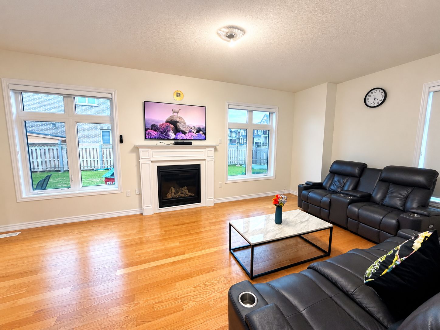 A living room with a fireplace, a television, a sofa, and large windows.