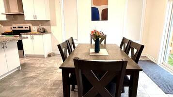 A modern kitchen with white cabinets, a dining table with six chairs, and a decorative vase with flowers.