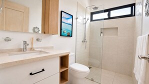 Een moderne badkamer met een douchecabine van glas, een toilet en een wastafel met spiegel erboven.