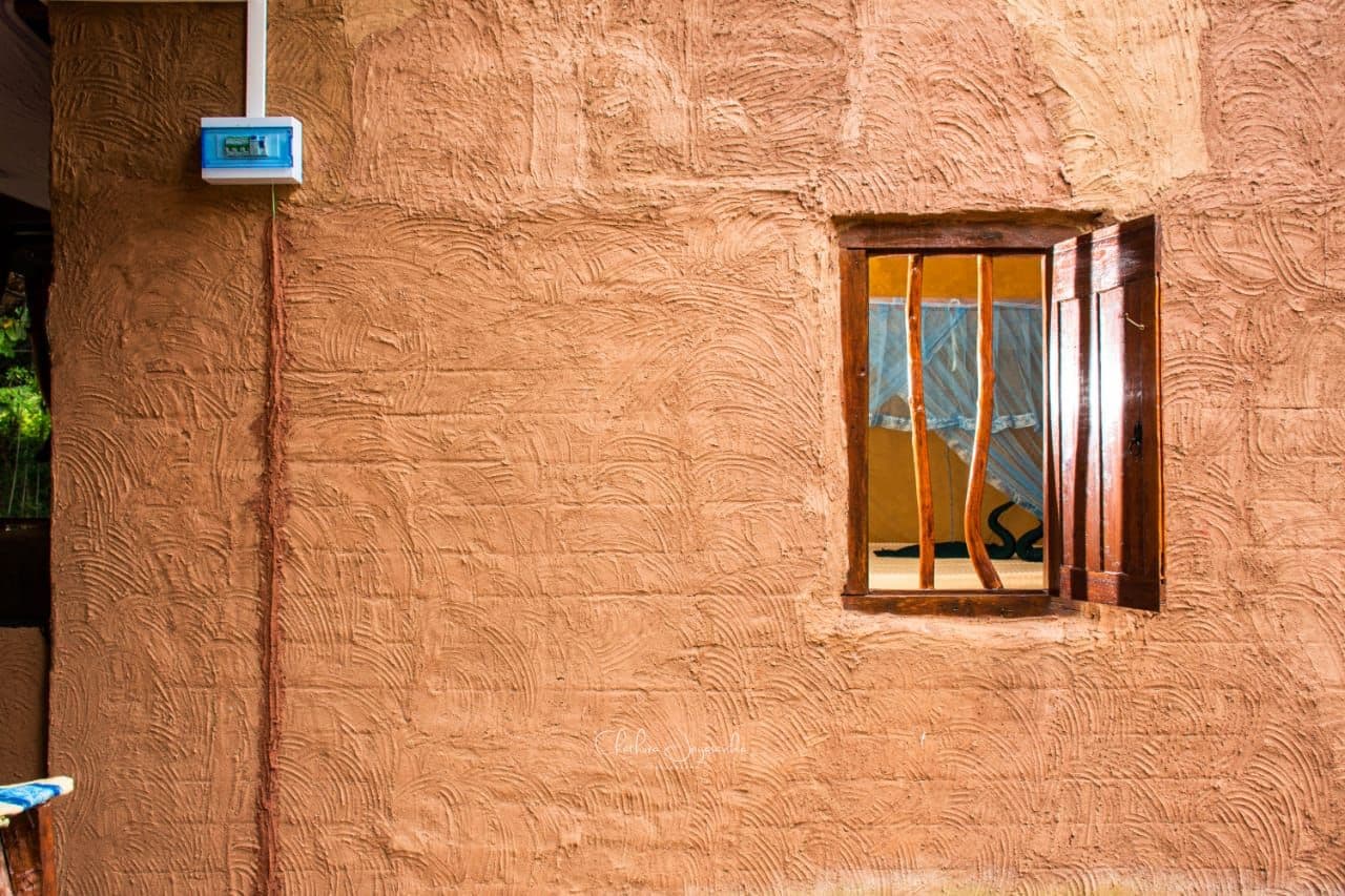 A textured wall with a window and a utility box.