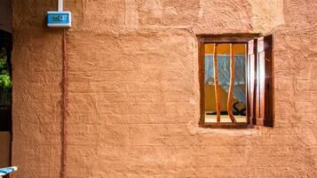 A textured wall with a window and a utility box.