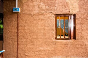 A textured wall with a window and a utility box.