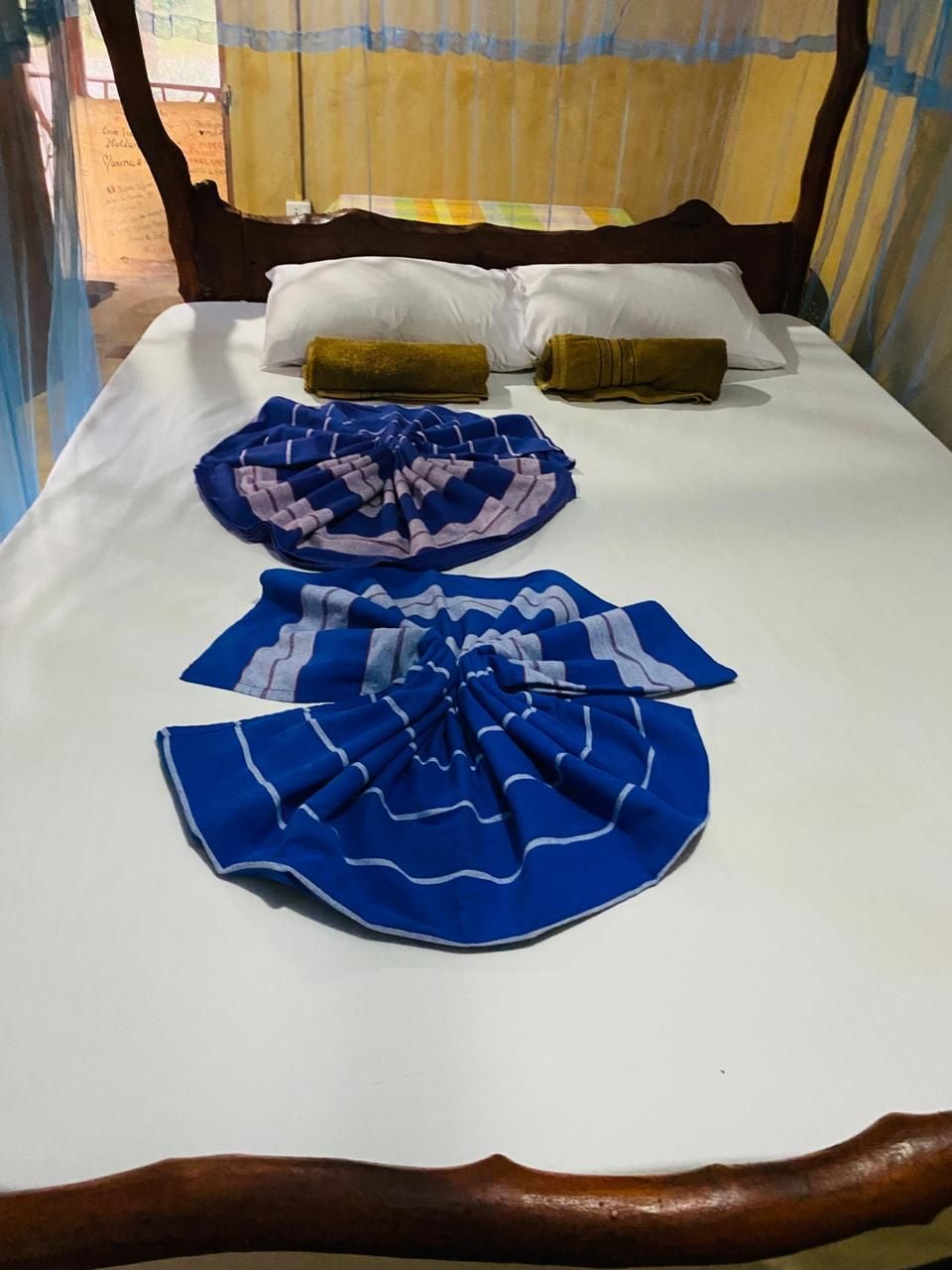 A bed with a wooden headboard, two pillows, and two folded blankets.